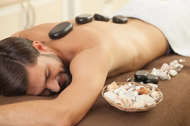 Hot stones arranged along a massage client’s back at Maison Forest Spa
